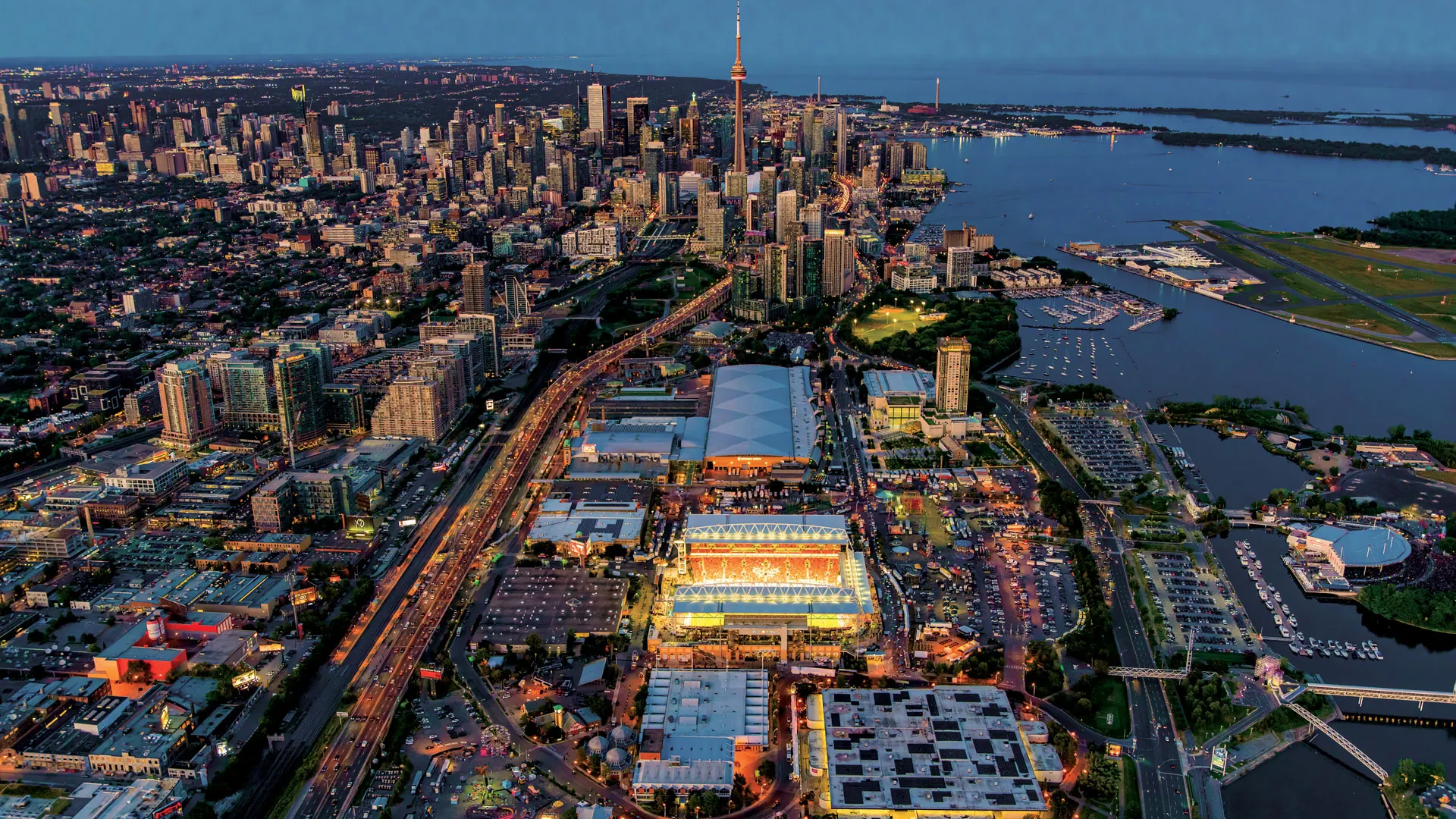 Aerial view at dusk of Exhibition Place, Liberty Village and the downtown Toronto skyline along the lake