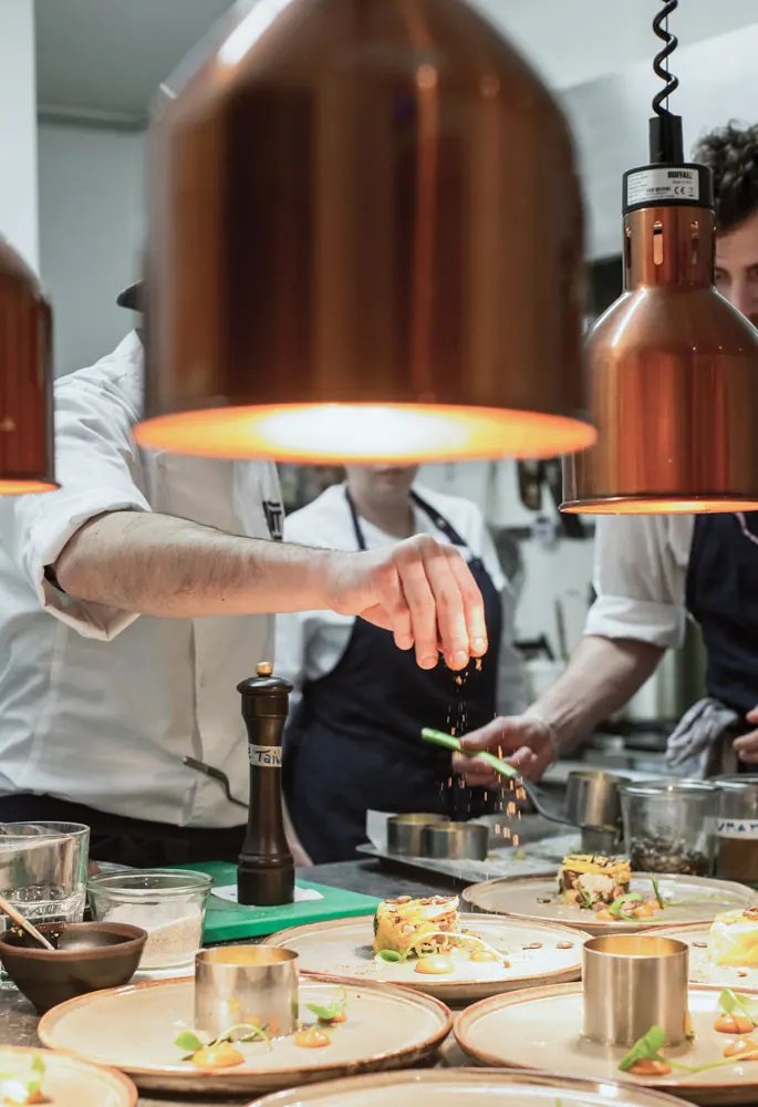 Chef plating dishes under copper heat lamps