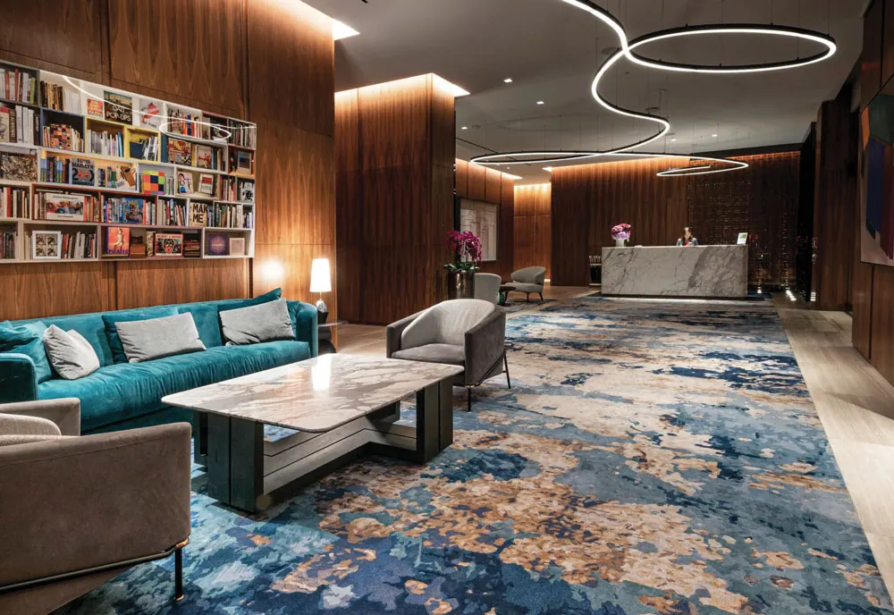 Lobby lounge at the Four Seasons Private Residences Toronto, with a library wall and teal sofa