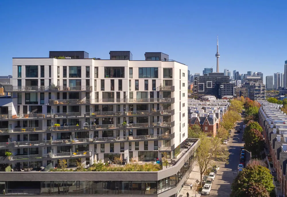 The Plant, a white mid-rise with planted balconies on Dovercourt Road, with the CN Tower beyond